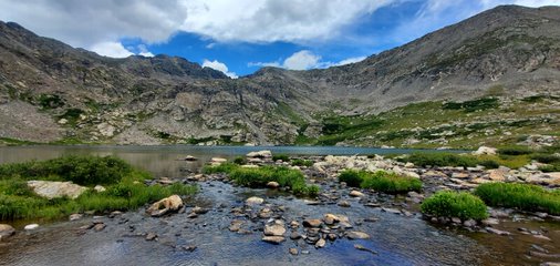 A mountain with water and rocks in the foreground